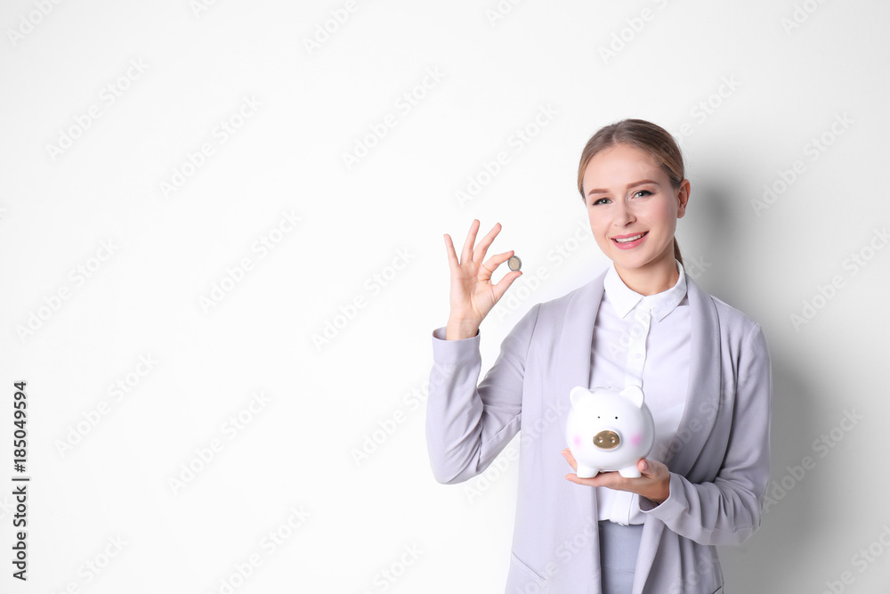 Young woman in formal clothes holding piggy bank and coin on white background Young woman in formal clothes holding piggy bank and coin on white background
