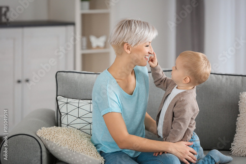 Attractive young mother playing with her baby on couch at home