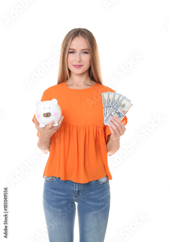 Young woman holding piggy bank and money on white background