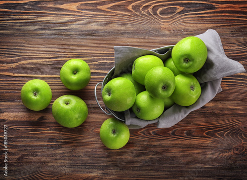 Basket with fresh green apples on wooden background