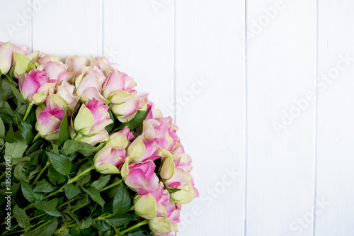 Fototapeta Naklejka Na Ścianę i Meble -  big bouquet of roses with pink petals and green on white wooden background
