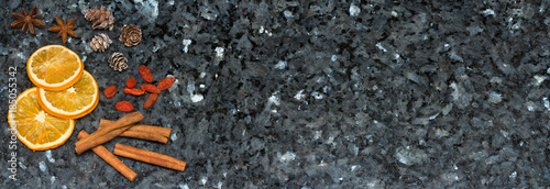 Orange slices, cinnamon, goji berries, pine cones, anise on emerald pearl granite worktop