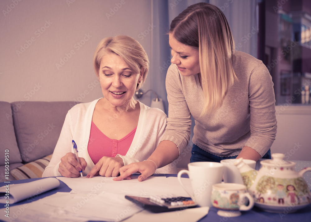 Fototapeta premium Daughter helps mother to lead home accounting