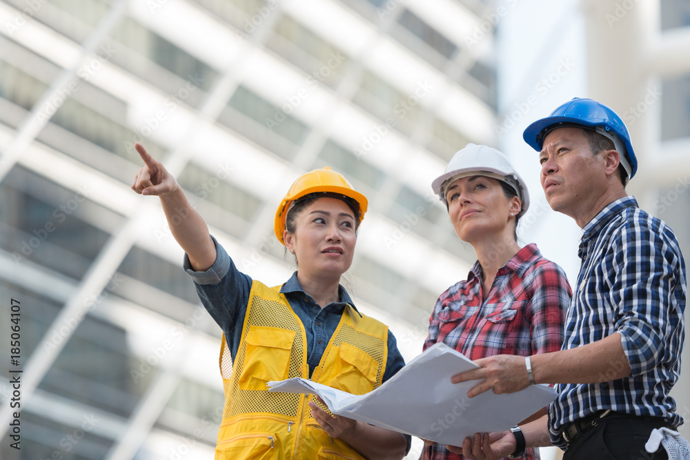 Asian engineers group consult construction on site building working while holding blueprint paper. in city background. teamwork concept. Asian engineers group consult construction on site building working while holding blueprint paper. in city background. teamwork concept.