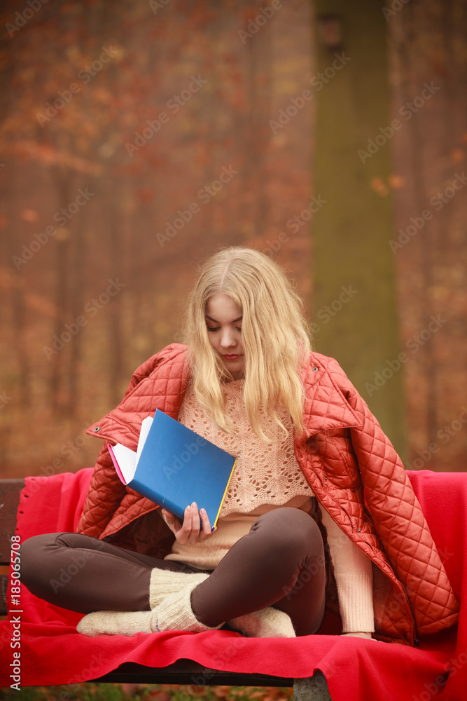 Obraz premium Blonde girl reading book in autumn scenery