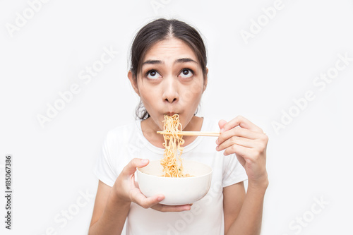 Young beautiful asian woman eating yummy hot and spicy instant noodle using chopsticks isolated on white background. Asian girl servile end of the month with cheap food. photo