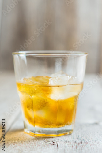 Glass with whiskey on the rustic wooden background. Selective focus. Shallow depth of field.