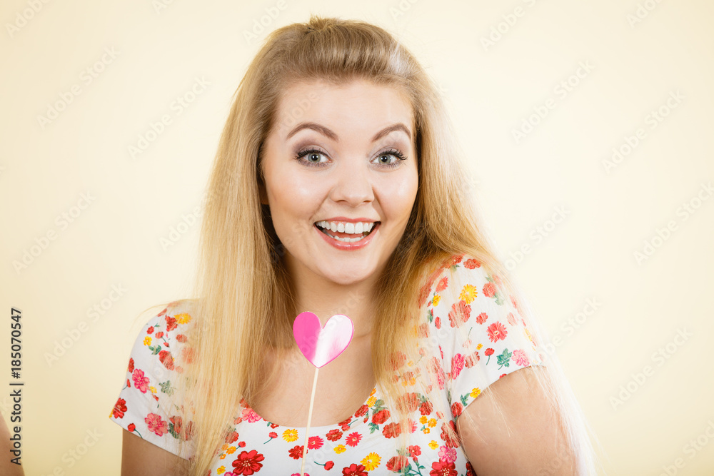 Happy woman holding heart on stick