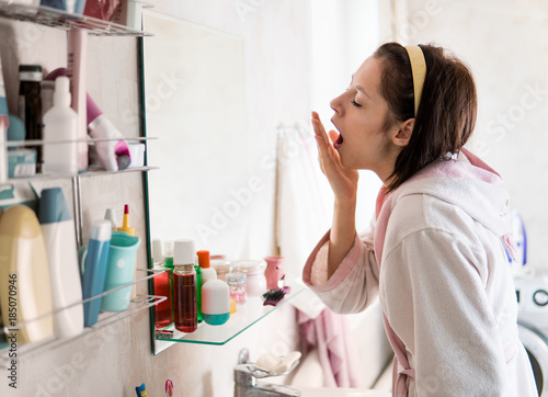 young woman in the bathroom yawns and wakes up