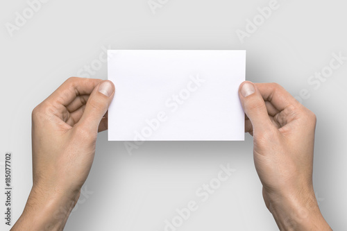 Empty white A6 postcard horizontally. Man holds a pattern in his hands on a gray background © adragan