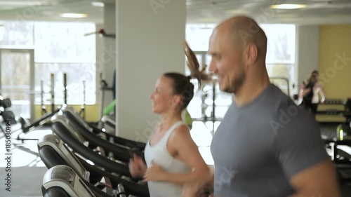 Man and woman are running on treadmill in sports club. Young couple jogged photo