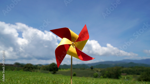 Paper windmill in the lawn with cloud and mountain background
