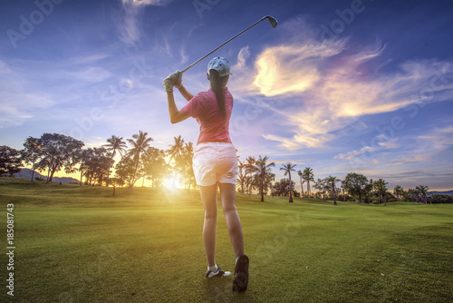 woman golf player at th end of downswing after hit a golf ball away from fairway to the green forward in a golf course