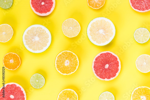 on a light yellow background, lie a sliced grapefruit with other fruits
