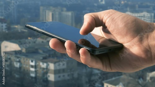 Close-up shot of man texting on smart phone against cityscape