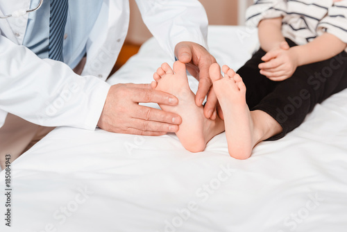 cropped shot of doctor examining childs feet in hospital