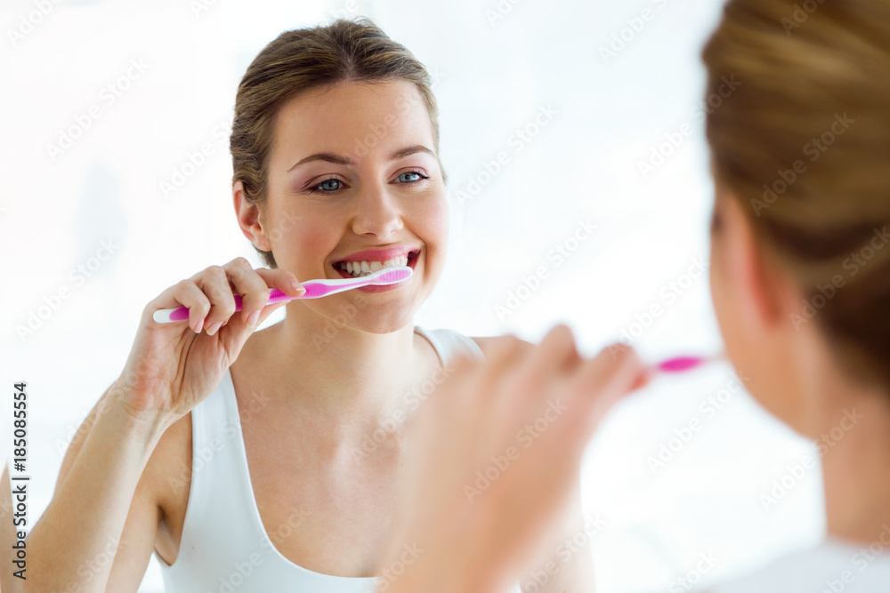 Pretty young woman brushing her teeth in the bathroom at home. Pretty young woman brushing her teeth in the bathroom at home.