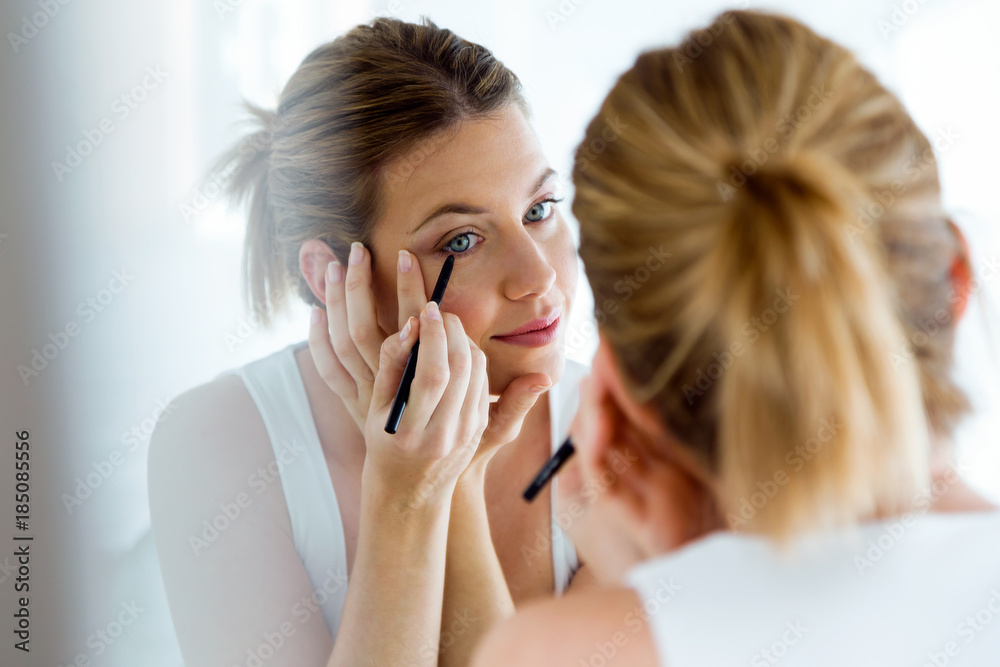Beautiful young woman doing make-up near mirror at home. Beautiful young woman doing make-up near mirror at home.