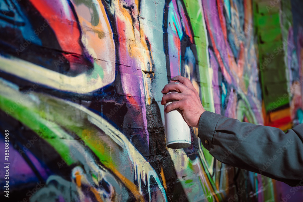 Obraz premium przycięty widok artysty ulicznego malującego graffiti farbą w aerozolu na ścianie w nocy