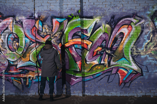 back view of street artist painting colorful graffiti on wall at night © LIGHTFIELD STUDIOS