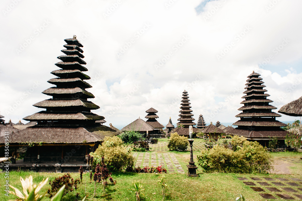 Temples in Pura Penataran Agung Besakih complex, the mother temple of Bali Island, Indonesia. Green lawn with several balinese temples with multistage roofs. Travel and architecture background Temples in Pura Penataran Agung Besakih complex, the mother temple of Bali Island, Indonesia. Green lawn with several balinese temples with multistage roofs. Travel and architecture background