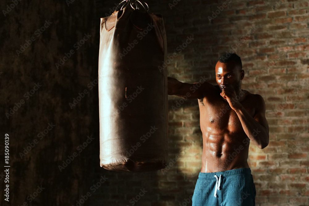 Φωτογραφία An African American guy trains in a vintage gym and fists his boxing bag fists