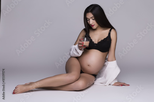 A wonderful pregnant girl lies in a black underwear