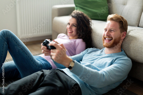 Happy couple playing video games at home