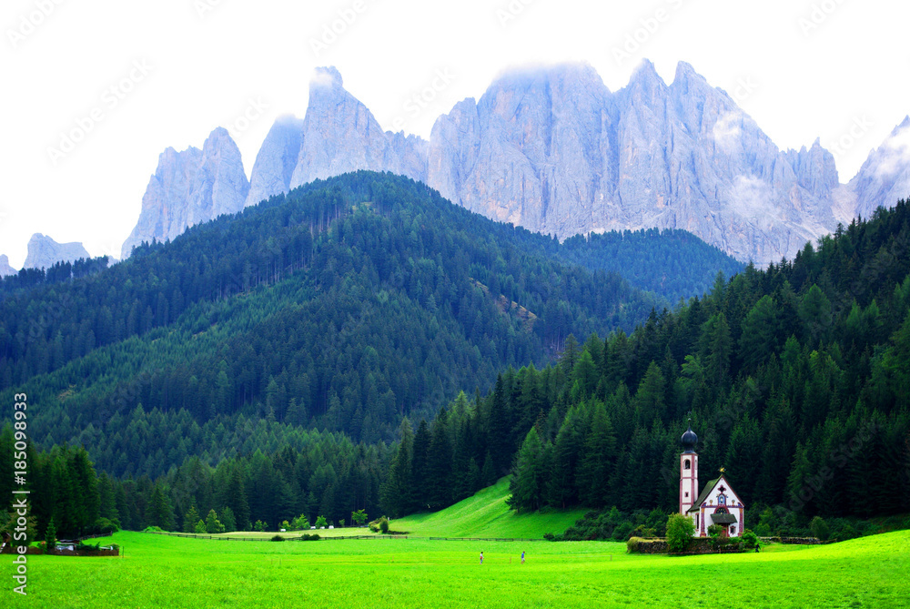 small church in the green meadow under the rocky mountains