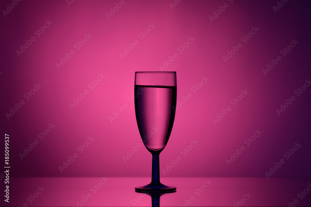 Wine in a glass goblet on a pink background with a gradient spot and stream of light on dark tones Wine in a glass goblet on a pink background with a gradient spot and stream of light on dark tones