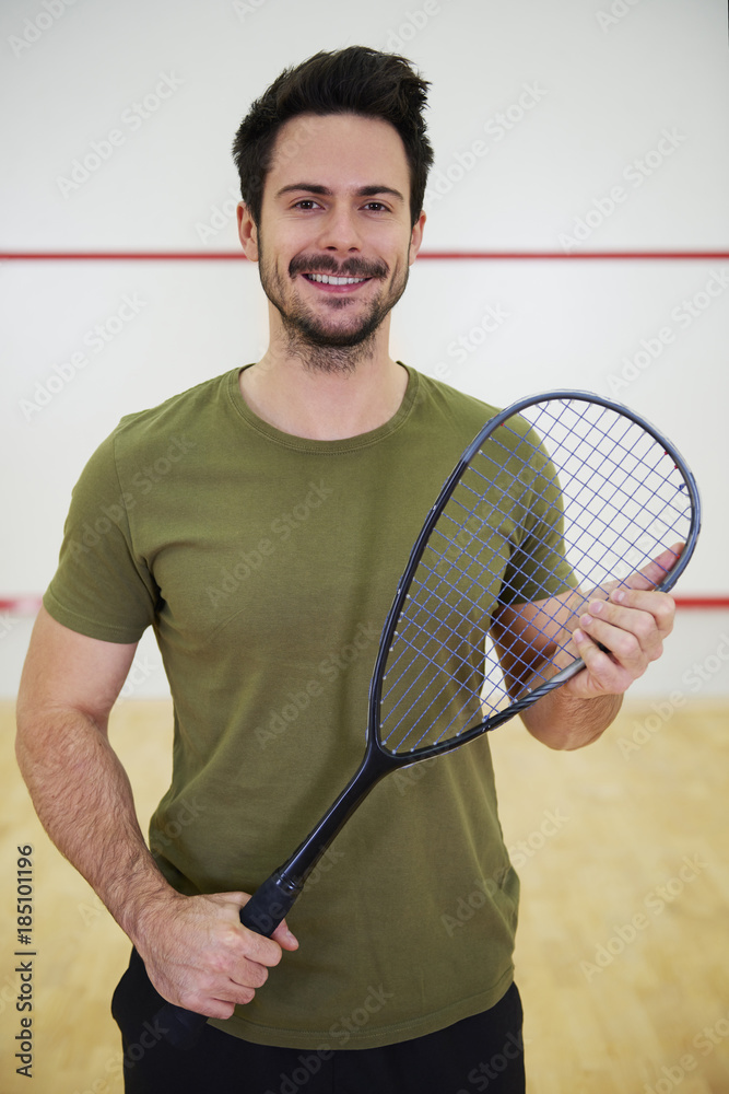 Portrait of male squash player with racket on court