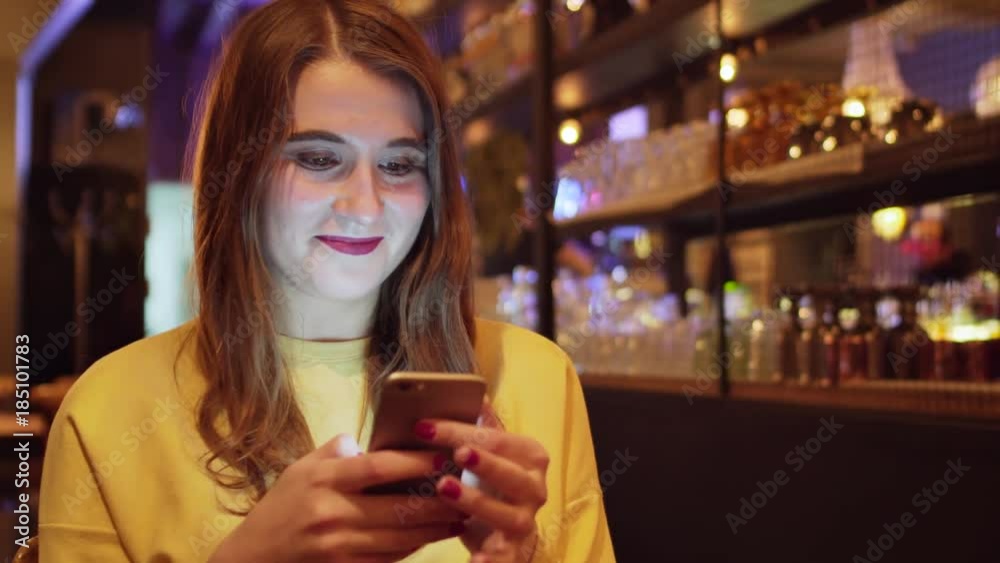 Girl texting on the smart phone in a restaurant Girl texting on the smart phone in a restaurant