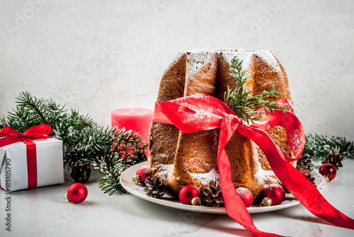 Traditional Italian Christmas fruit cake Panettone Pandoro with festive red ribbon and Christmas decorations, on white background, copy space photo