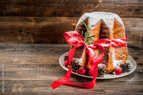 Traditional Italian Christmas fruit cake Panettone Pandoro with festive red ribbon and Christmas decorations, on wooden home background, copy space photo