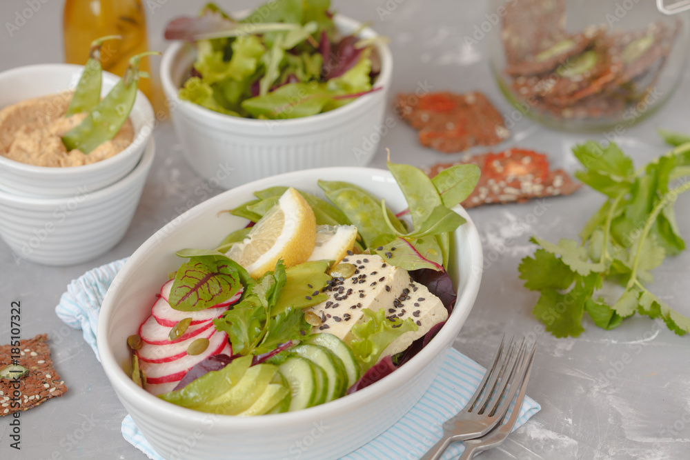 Green salad, buddha bowl with tofu, vegetables, hummus with flax crispbread.