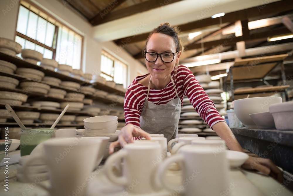 Woman checking mugs at worktop