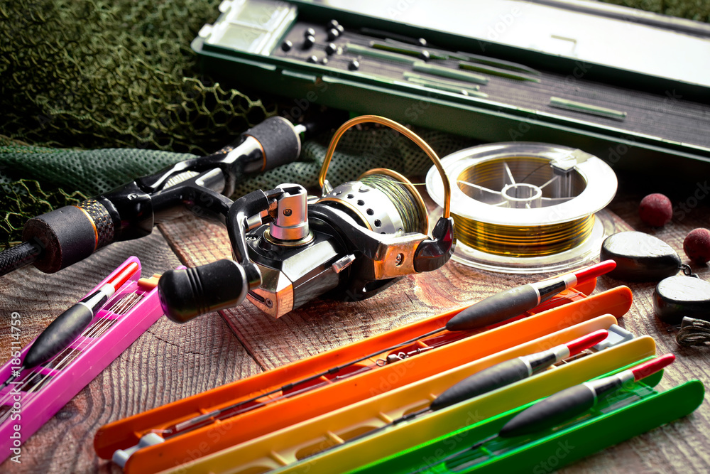 Fishing rods and spinnings in the composition with accessories for fishing on the old background on the table