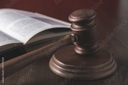 opened juridical book with hammer on wooden table, law concept