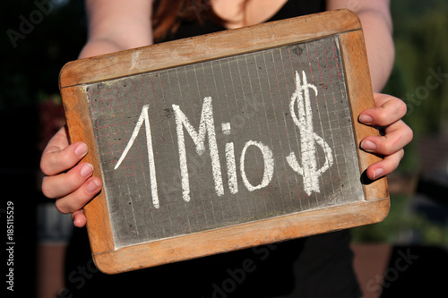 1 MIO $ written with chalk on slate shown by young female