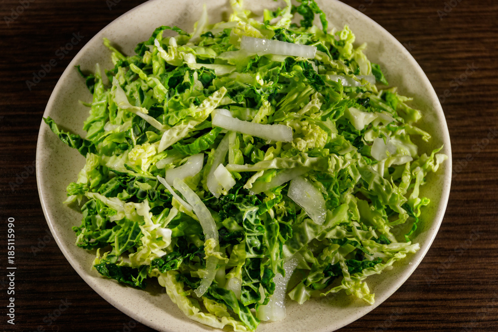 Salad with savoy cabbage and onion on wooden table Salad with savoy cabbage and onion on wooden table