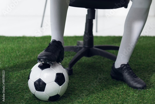 cropped shot of businessman in football boots with soccer ball