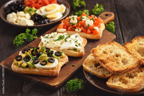 Variety of sandwiches with tomatoes, mozzarella, avocado, eggs and cream cheese.