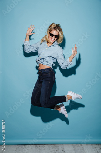 Full length image of Pleased blonde woman in shirt and sunglasses