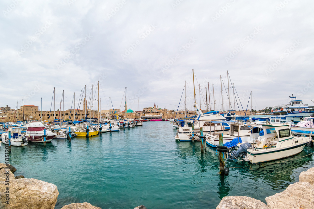 View on marina with yachts and ancient walls of harbor in Acre.