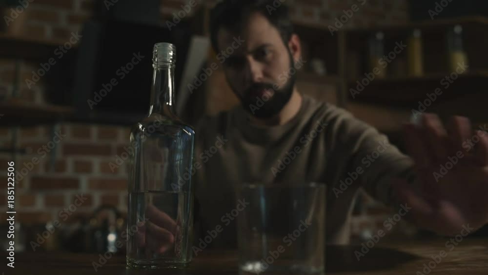 Enough. Young bearded man putting his glass away while waving his hand and being against alcohol Enough. Young bearded man putting his glass away while waving his hand and being against alcohol