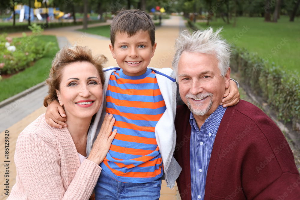 Happy senior couple with grandson in park