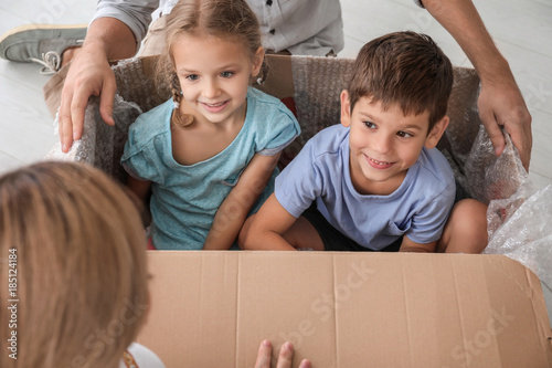Children playing with cardboard box after moving to new flat © Africa Studio