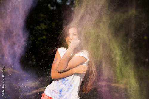Emotional young asian woman with long hair posing in a cloud of Holi paint