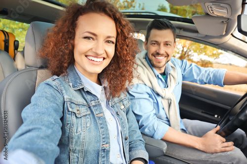 Happy young couple taking selfie in car