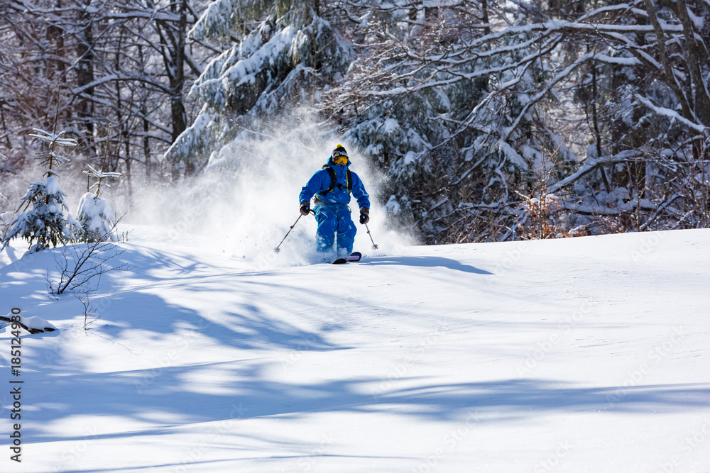 A skier is riding downhill in the deep snow. A skier is riding downhill in the deep snow.